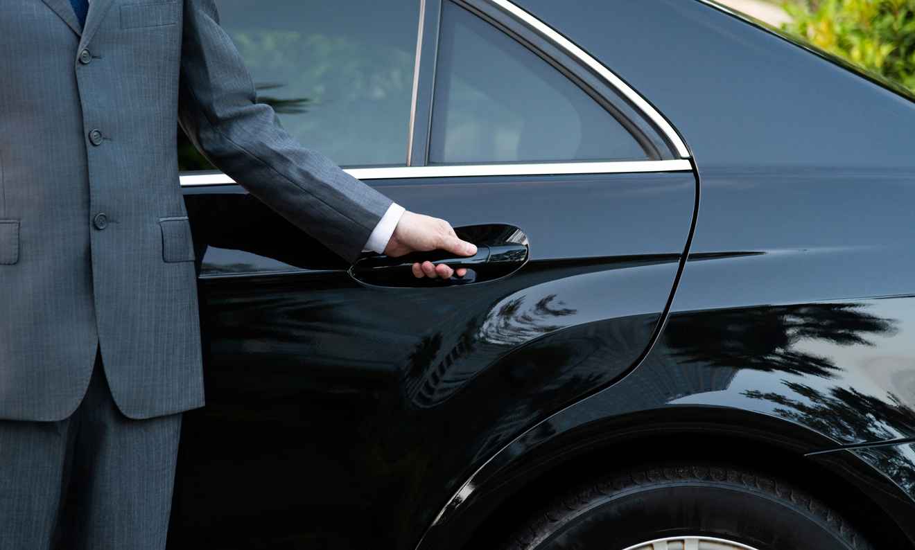 unrecognizable well dressed male chauffeur opening a car door