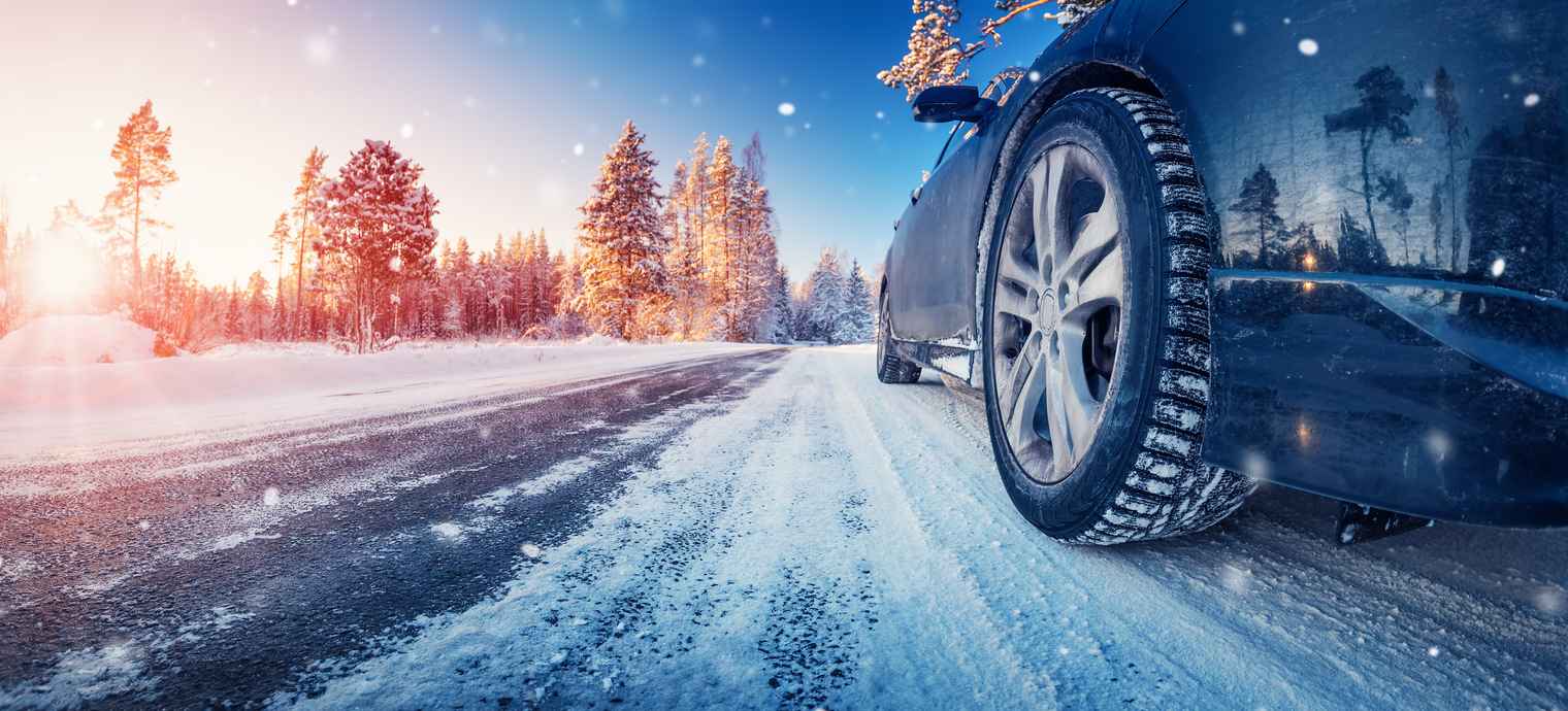 Closeup view of the car's wheel on the snowy road in natural park. Beautiful panoramic view.